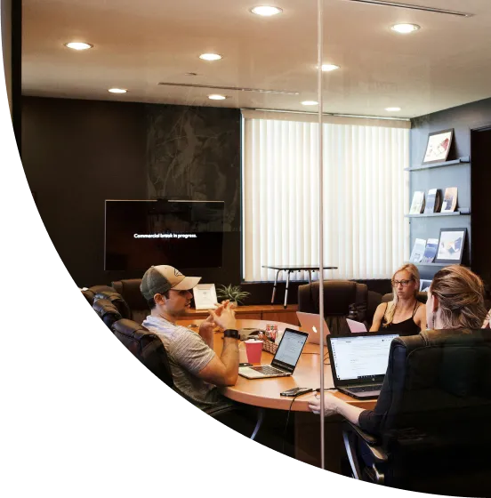 A group of people sitting around a table with laptops.